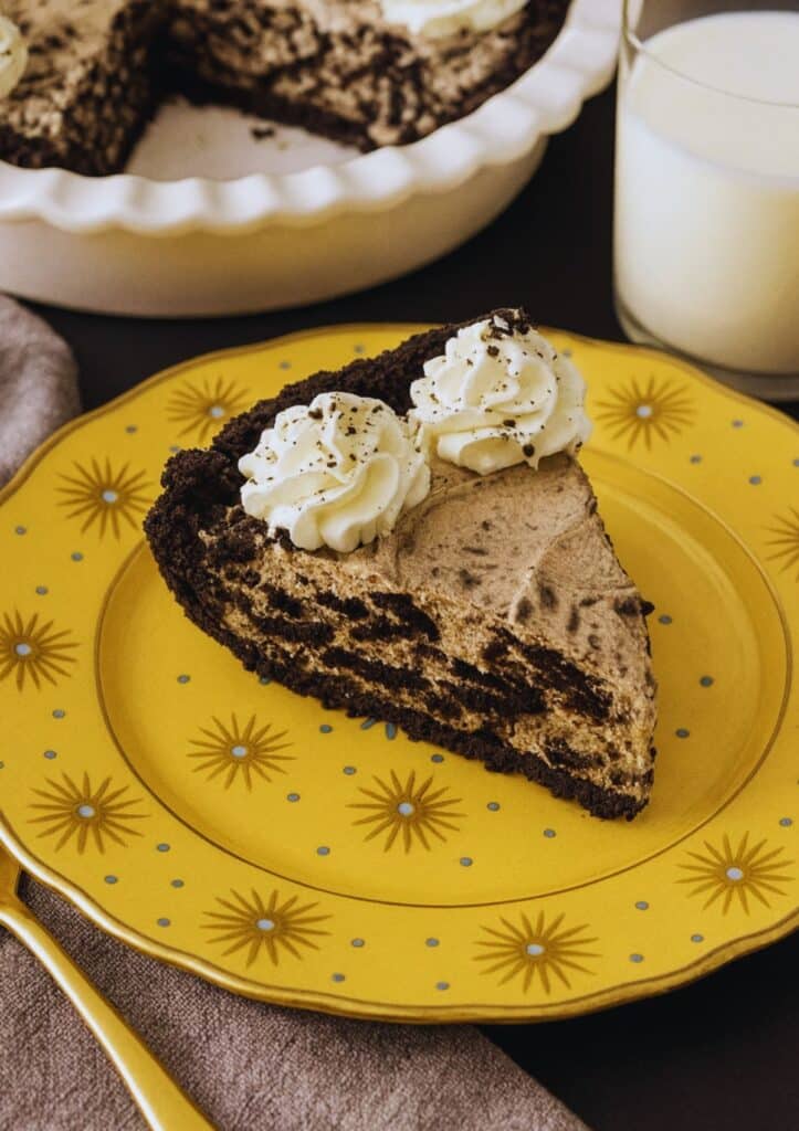 Slice of Oreo pie on a yellow plate decorated with golden sunbursts and blue dots