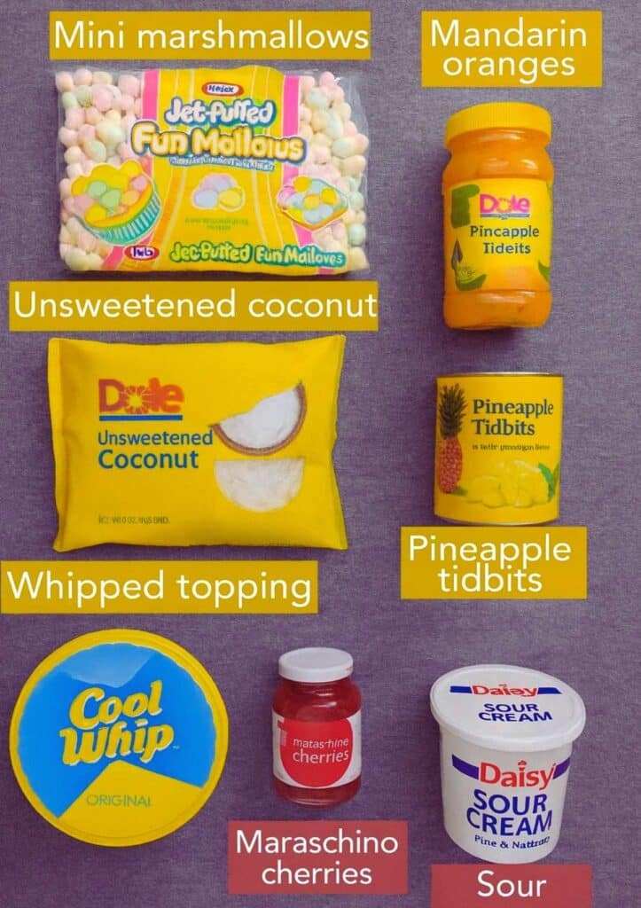 ambrosia salad ingredients including whipped topping, mini marshmallows, pineapple, oranges, cherries, coconut, and sour cream