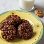 No Bake Cookies on a yellow plate with golden rim beside a glass of milk