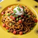 Taco Spaghetti Recipe served on yellow sunburst plate in cozy kitchen