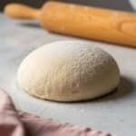 Ball of homemade pizza dough on floured marble countertop