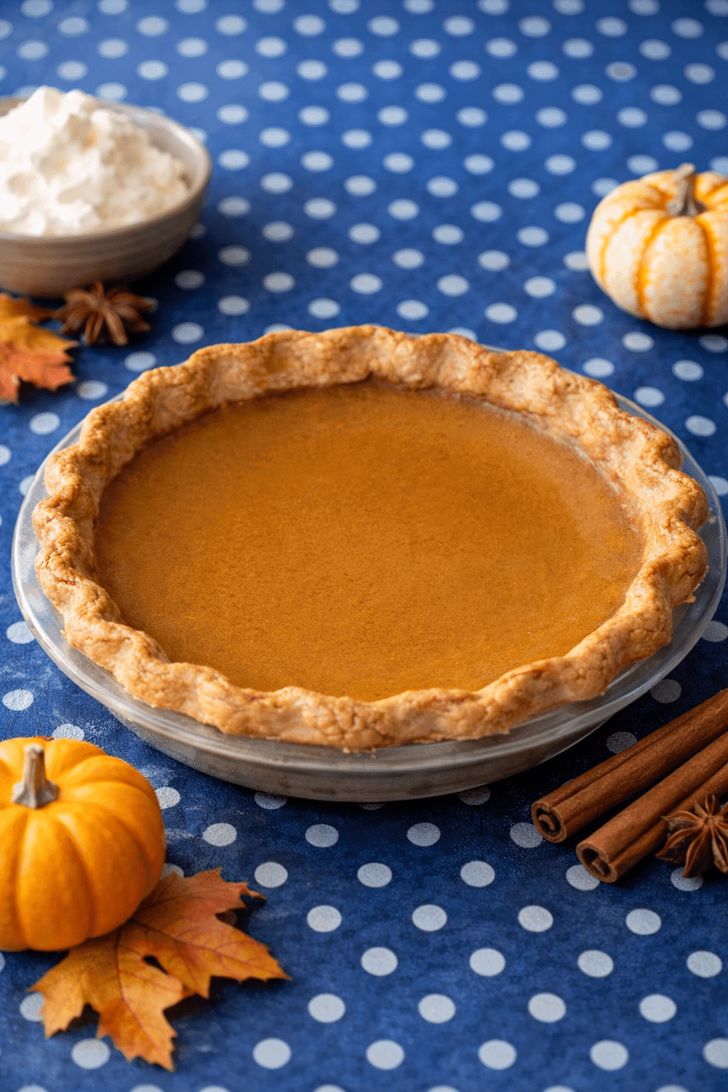 Homemade pumpkin pie surrounded by mini pumpkins and fall leaves