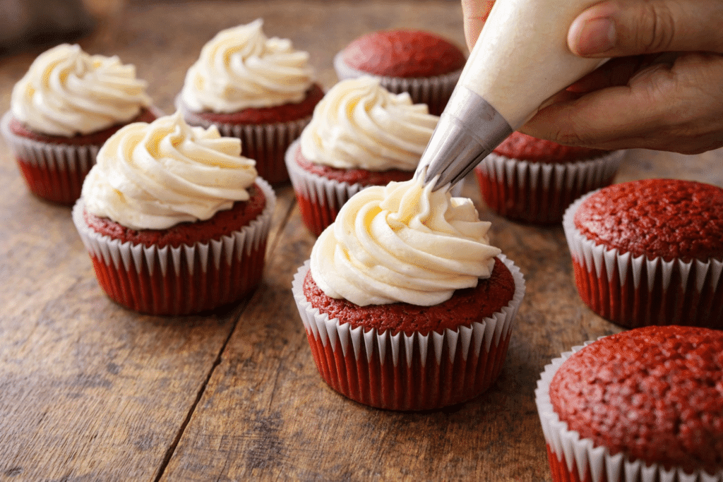Piping cream cheese frosting onto Red Velvet Cupcakes